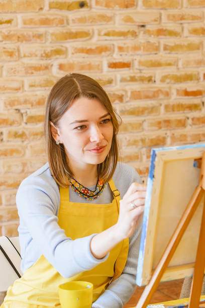 istock Woman with brush painting on canvas 1553043041
