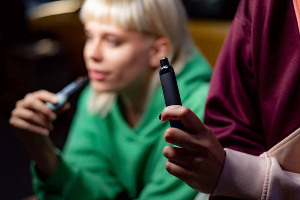 Close up of smoking a vape. Close up of unrecognizable woman smoking electronic cigarette with her friend. electronic cigarette stock pictures, royalty-free photos & images