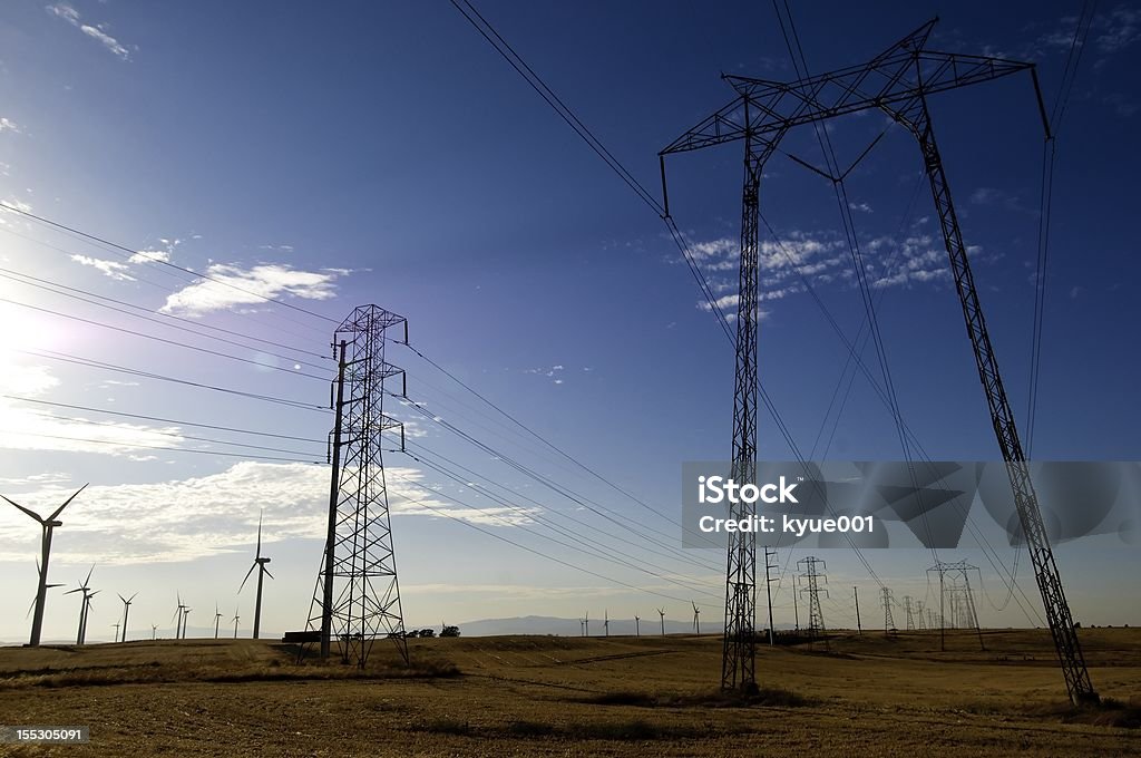 Wind Turbines Power Grid Power lines running through the Wind Farm with blue sky as background. Environmental Conservation Stock Photo
