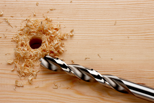 Drill bit with newly drilled hole and wood shavings