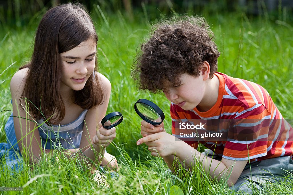 Kids using magnifying glass outdoor Kids using magnifying glass 12-13 Years Stock Photo