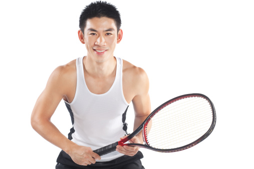 Handsome and fit Chinese tennis player poses with his racket, ready to play.  