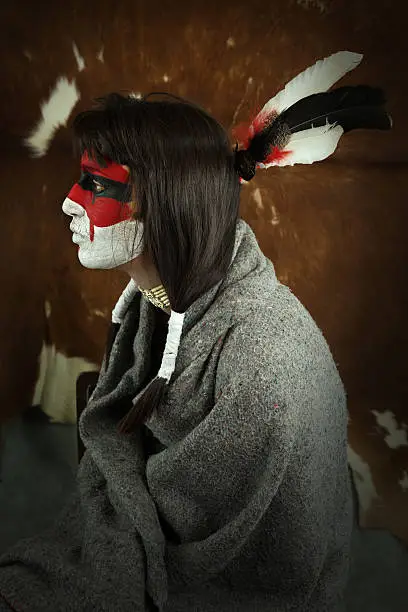 Native american woman portrait with painted face. Young beautiful woman in native american costume with wool cloak and war mask on her face