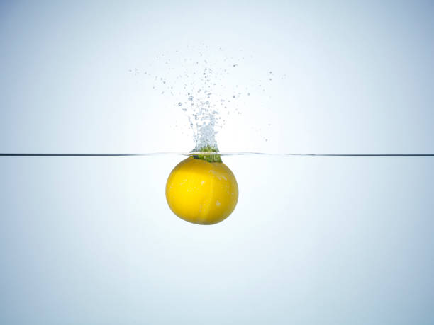 Cut orange sinking underwater with splashes on white
