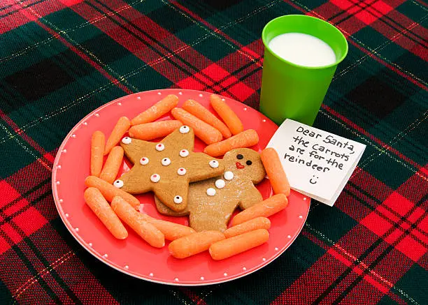 A plate filled with gingerbread cookies and carrots is set out for Santa and his reindeer on Christmas Eve.