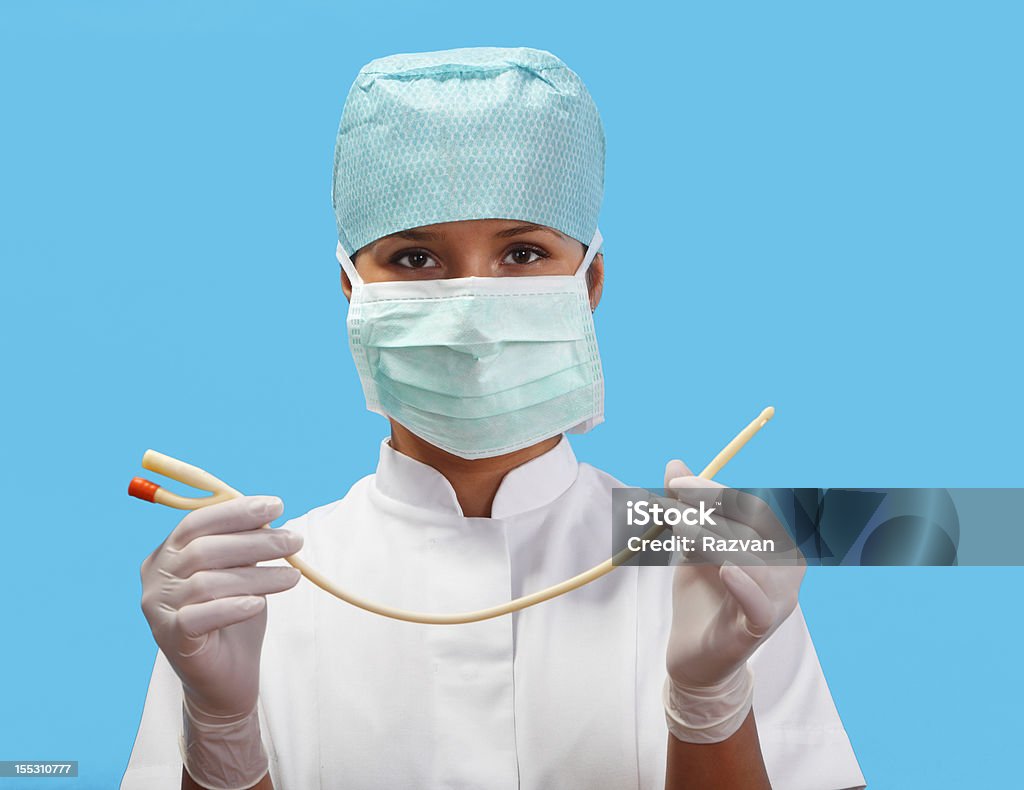 Female Nurse With An Urinary Catheter Female nurse holding an urinary catheter isolated against a blue background. Catheter Stock Photo