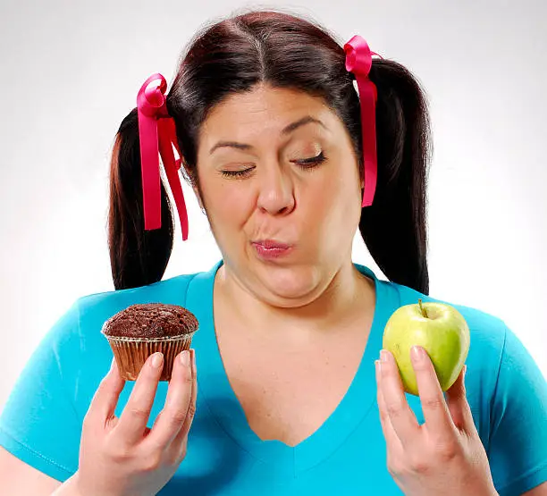 One young fat woman holding a chocolate cake and apple.