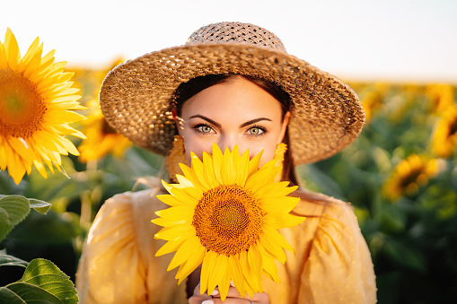 Pretty woman in retro dress posing in sunflowers field. Yellow colors, warm toning. Vintage timeless fashion, amazing adventure, countryside, rural scene, natural lifestyle.