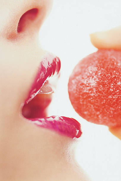 woman biting red candy stock photo