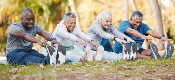 Fitness, stretching and senior people in park for healthy body, wellness and active workout outdoors. Retirement, sports and men and women stretch legs on grass for exercise, training and warm up fitness, estiramientos y personas mayores en el parque para un cuerpo saludable, bienestar y entrenamiento activo al aire libre. jubilación, deportes y hombres y mujeres estiran las piernas sobre el césped para hacer ejercicio, entrenar y calentar