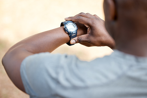 African man, check smart watch and fitness in park to monitor speed, heart or vital signs. Outdoor, male runner and iot clock for time, training or exercise with stopwatch, nature and summer sunshine