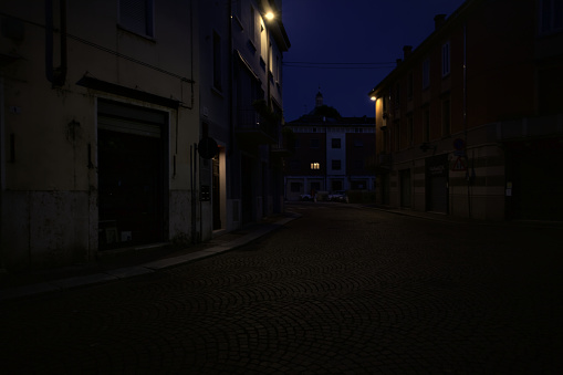 Crossing  between streets lit by lamps in an italian town at dusk