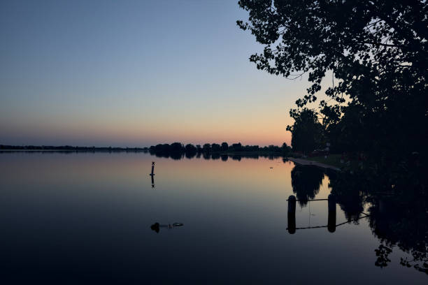 brzeg rzeki o zachodzie słońca z odbiciem rzuconym w wodzie o zachodzie słońca widzianym z daleka - riverside night reflection italy zdjęcia i obrazy z banku zdjęć