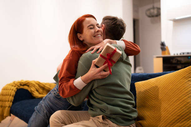 istock Overjoyed happy young woman holding gift box hugging husband feeling excited 1553167155