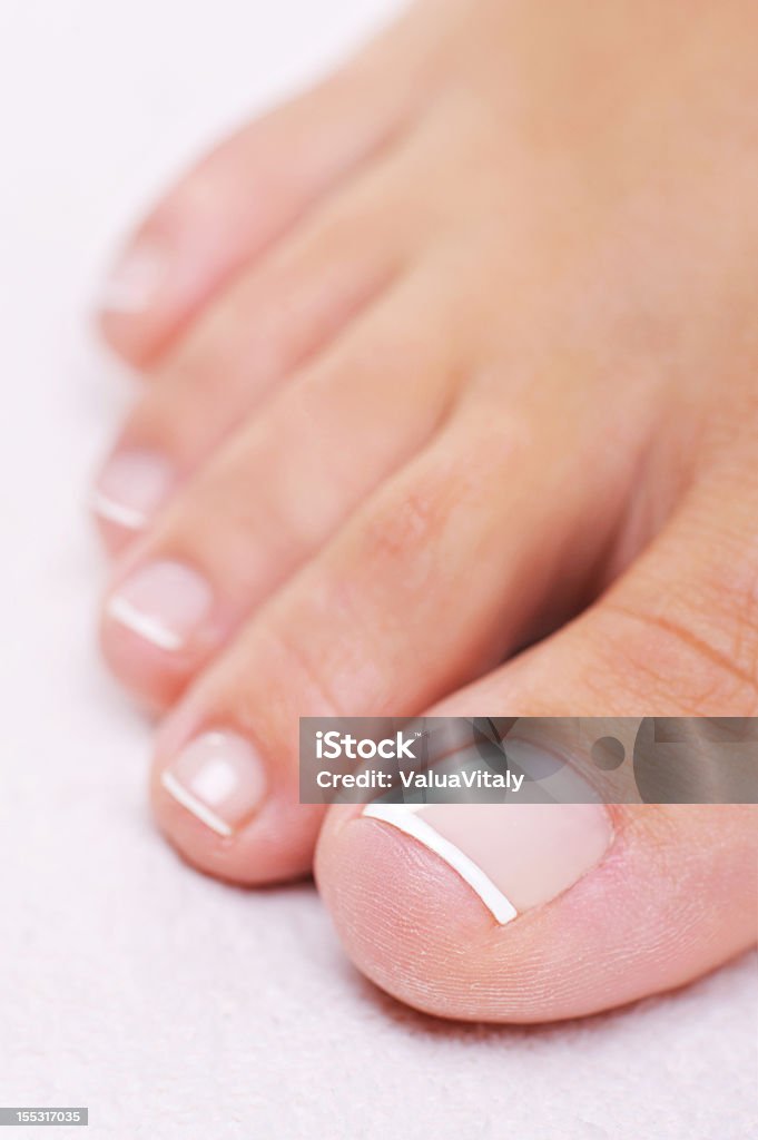 well-groomed female foot with a french pedicure Single well-groomed female foot with a french pedicure. Close-up toy. High Angle View Stock Photo