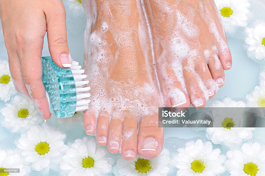 Woman washes and cleans her foot The young woman washes and cleans the beautiful well-groomed legs in water by means of a clearing brush Washing Stock Photo