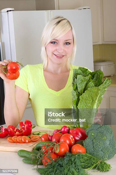 Giovane Donna Bionda Mette Con Verdure In Cucina - Fotografie stock e altre immagini di 25-29 anni - 25-29 anni, Abbigliamento casual, Adulto
