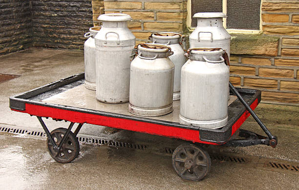Milk Churns. Vintage Milk Churns on a Trolley on a Rainy Day. butter churn stock pictures, royalty-free photos & images