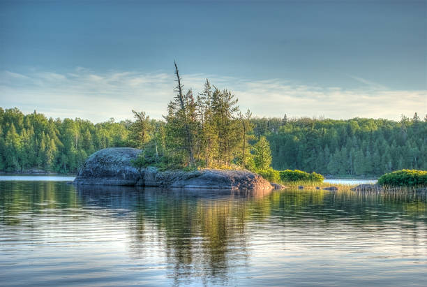 Rock Island at Sunset A small, rocky island reflecting off of a wilderness lake at sunset   boundary waters canoe area stock pictures, royalty-free photos & images