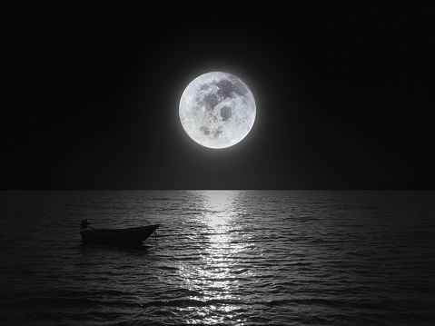 Bright and beautiful dramatic super moon over the ocean with small boat and reflection of bright light in black and white. Image use for imply  loneliness mood background.  moon image : https://www.nasa.gov/mission_pages/apollo/40th/images/apollo_image_25.html