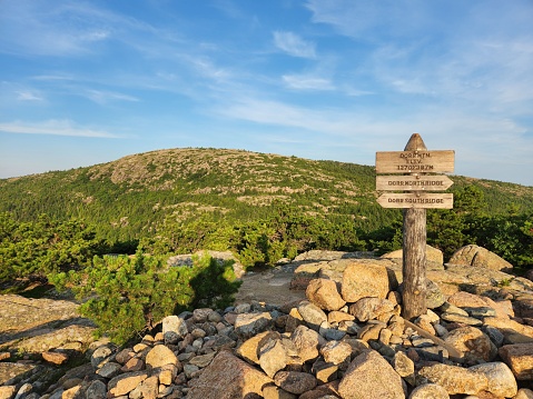 A wooden signpost perched atop a pile of rocks. Dorr Ridge, Acadia National Park, Maine, USA.