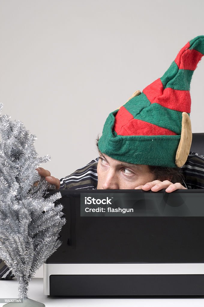 Человек, скрывая под ноутбук с Эльф шляпа - Стоковые фото Беспроводная технология роялти-фри