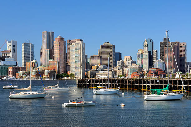 Boston Skyline and Sailboats Boston skyline across the harbor. Old dock and sailboats in the foreground, modern office and apartment buildings in background   east boston stock pictures, royalty-free photos & images