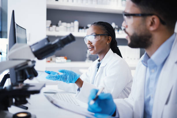 istock Scientist man, woman and checklist in laboratory with microscope, pc or analysis for virus dna at pharma job. Teamwork, medical research and digital touchscreen for data, info and study for wellness 1553232349