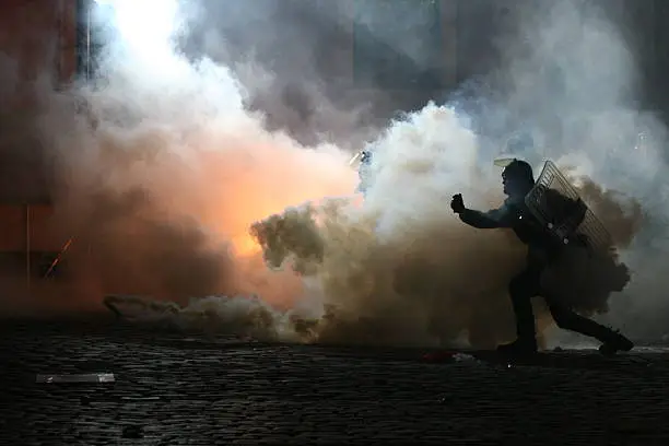 A policeman throws smoke gas at demonstrators.