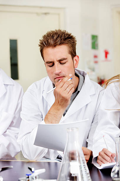 Puzzled lab worker scratches chin stock photo