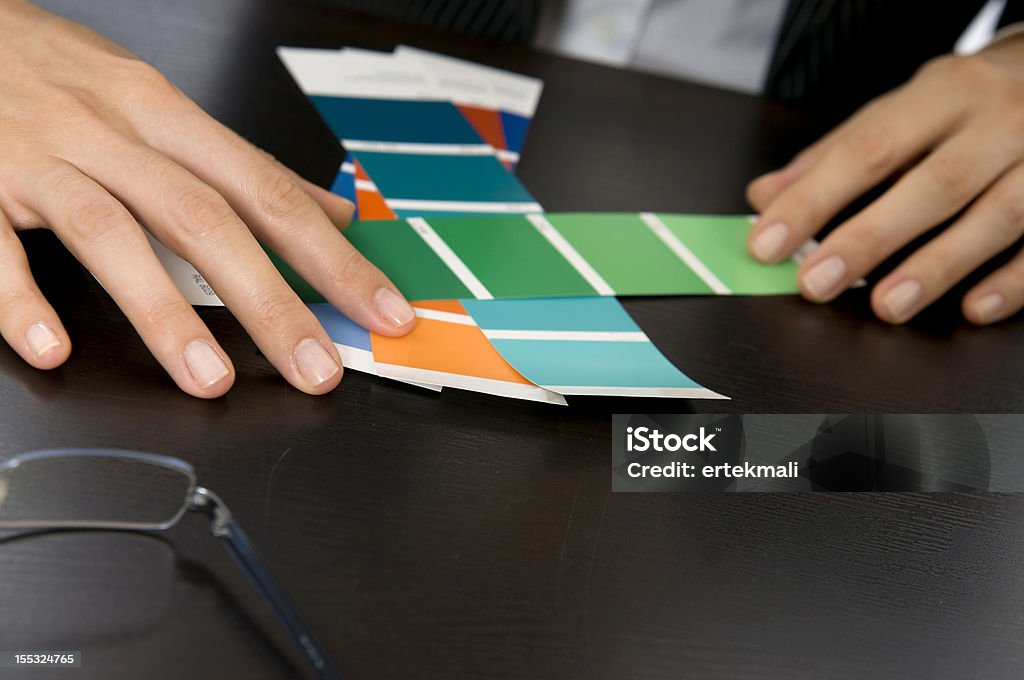 Woman's Hands Picking Out Swatches A close up of a woman's hands looking through swatches. Her eye glasses are off to the side and in the background you can see her blurred business suit. Blue Stock Photo