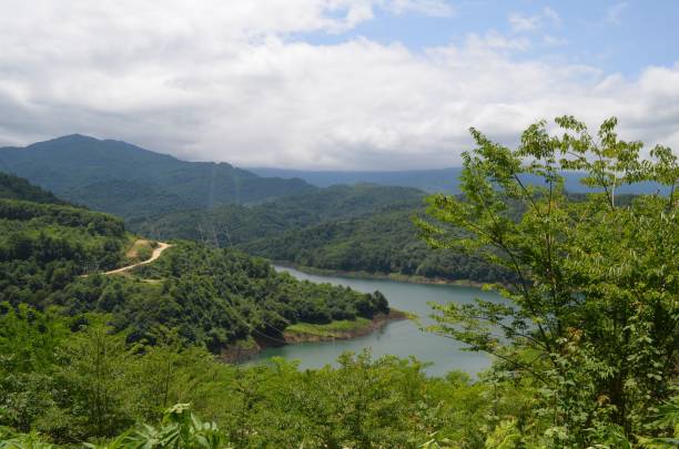 istock Landscape of a river surrounded by hills and greenery under a blue cloudy sky 1553250152