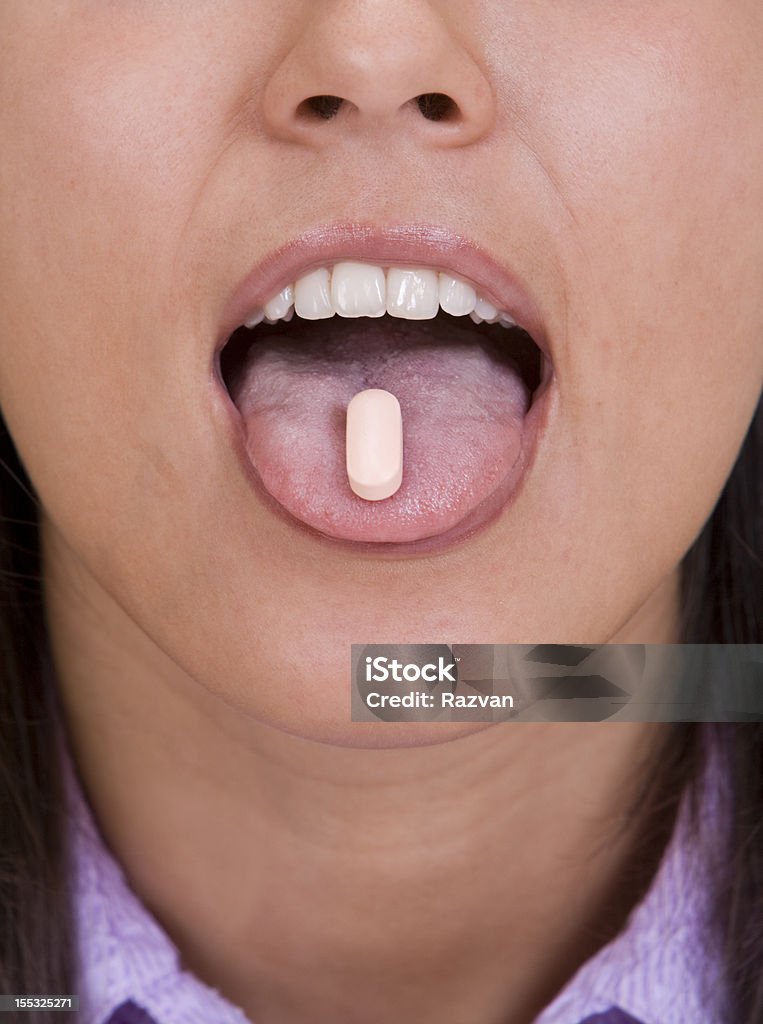 Pill on the tongue Close-up image of a woman's mouth with a pill on her tongue. Adult Stock Photo