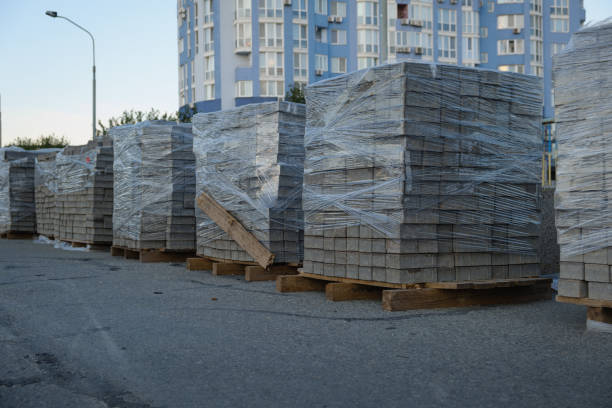 Packed paving slabs stacked on the street: piles of building materials on the street are ready for use in the construction of the sidewalk. Gray brick for laying the sidewalk.