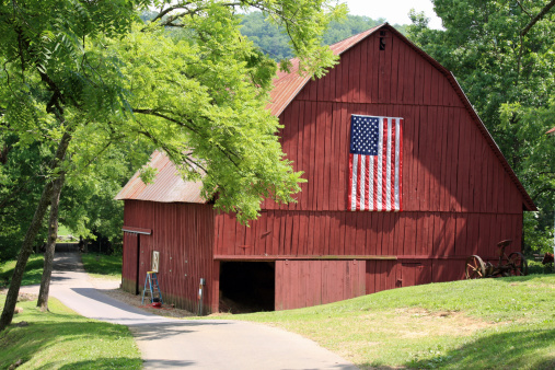 Red barn on a farm, with an American flag.  