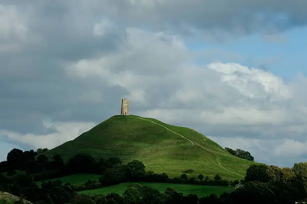 Glastonbury Tor half in shade with clouds overhead