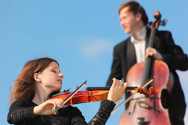 istock Violinist and violoncellist play against sky 155326859