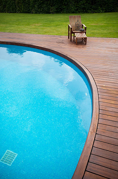 Wooden deck chair and swimming pool stock photo
