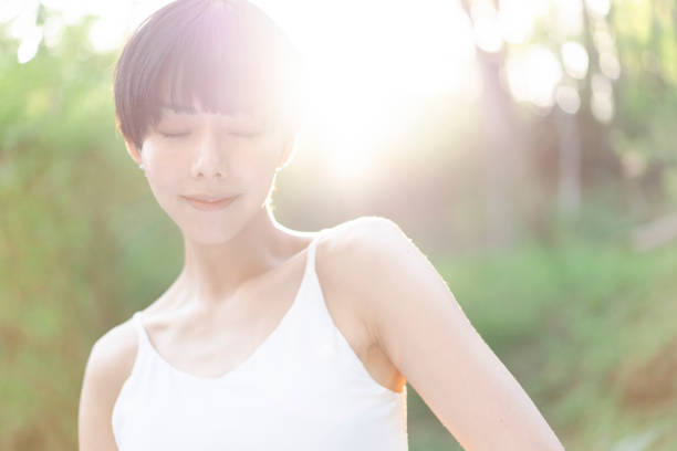 Young Asian woman's beauty portrait.  she is standing in forest. Sunlight is shining. Backlight.