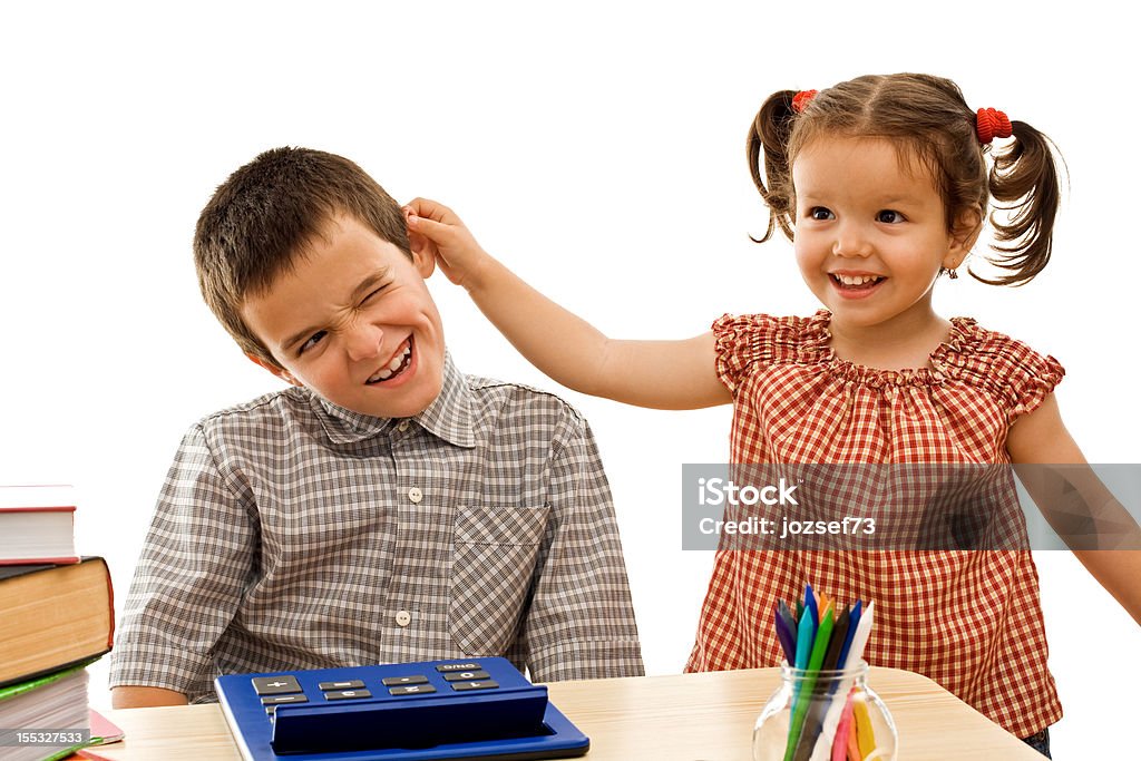 Dziewczynka trzymać chłopiec jego ucha - Zbiór zdjęć royalty-free (Biurko)