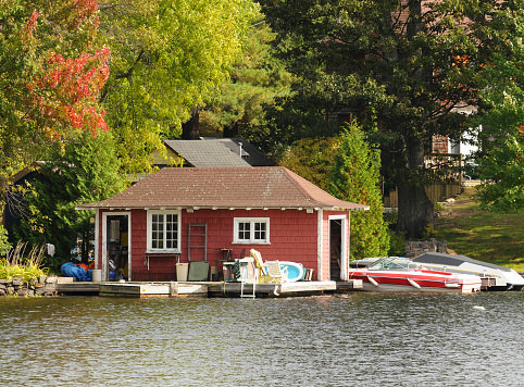 Wooden boathouse with two boats in autumnal setting