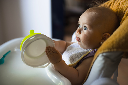 Infant baby holding a soft food bowl
