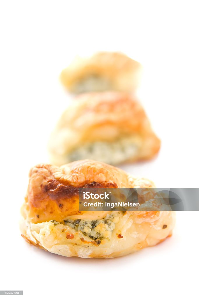 Puff pastry with cheese Three small gold brown pieces of puff pastry stuffed with cheese and fresh green herbs. Small depth of field. Canape Stock Photo