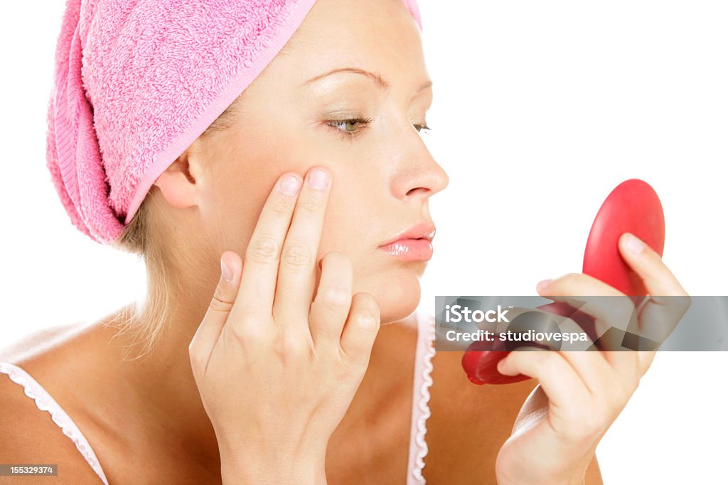 Young white woman looking in mirror Young beautiful woman examining her face in mirror. Blusher - Make-Up Stock Photo