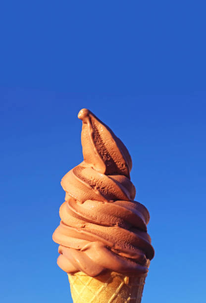 istock Chocolate Soft Serve Ice Cream Cone Against Sunny Vibrant Blue Sky 1553297955
