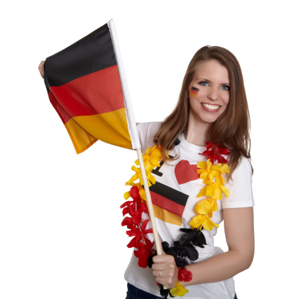 Attractive woman shows german flag and smiles in front of white background