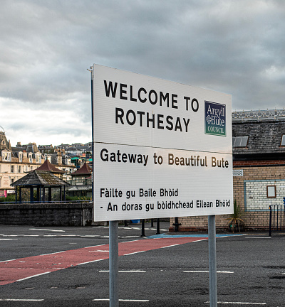 Rothesay, Scotland, UK - 13th July 2023: Welcome to Rothesay sign on the pier at the ferry harbour in Rothesay, on the Isle of Bute in the Firth of Clyde. The Victorian Toilets are behind the sign to the left.