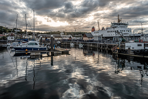 Rothesay, Scotland, UK - 13th July 2023: Yachts, recreational boats, a fishing boat and the MV Bute moored on a quiet summer evening in Rothesay Marina and Harbour, Isle of Bute. The Victorian Toilets can be seen on the pier.