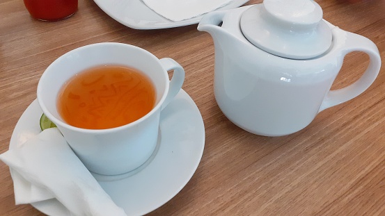 White cup of tea and pot tea on the table