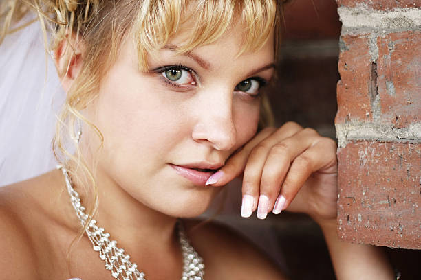 portrait of a beautiful young bride against brick wall stock photo